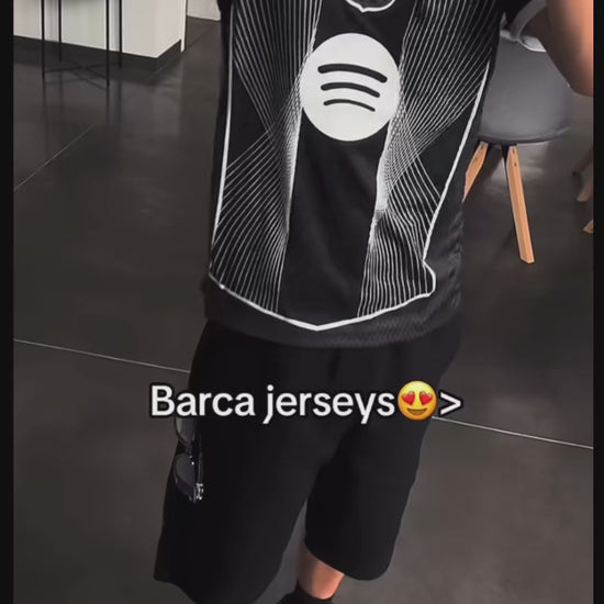 Person wearing black Barcelona jersey with logo and stripes